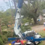 emergency tree removal crew removing storm-damaged tree from residential roof in Mississippi